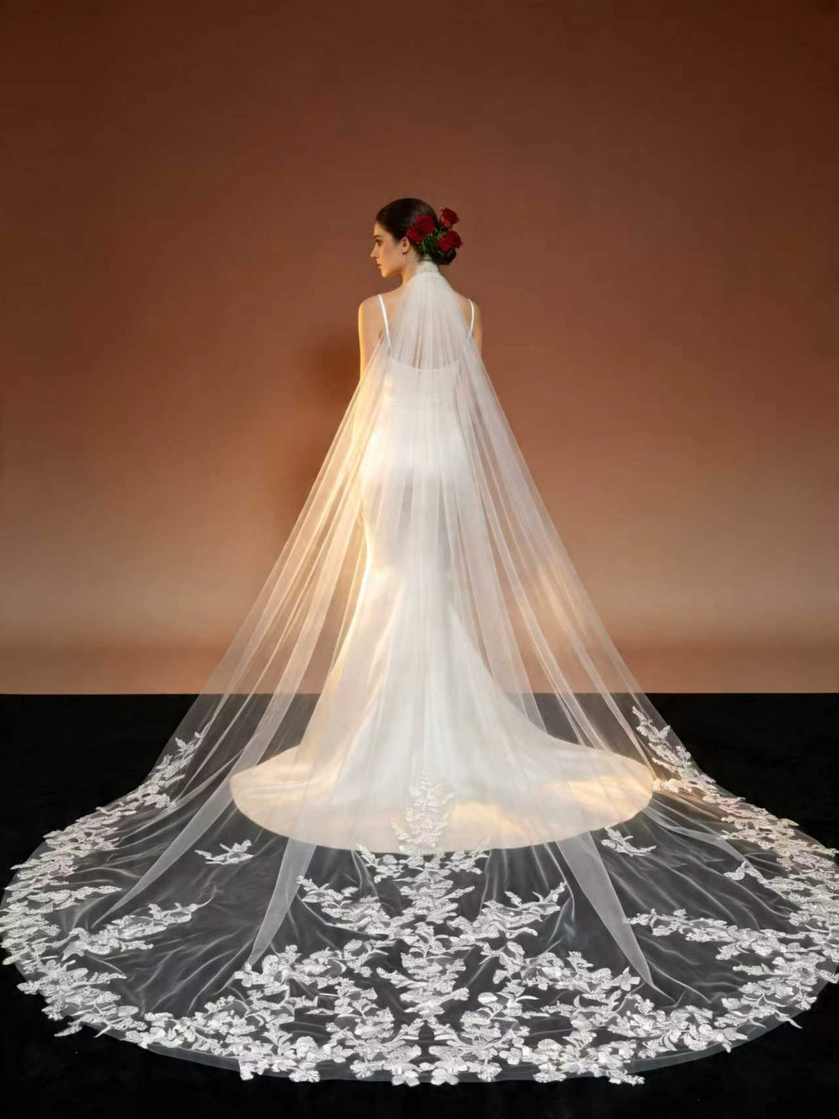 Warm studio shot of full floral lace cathedral wedding veil, backlit sheer tulle and glowing lace hem