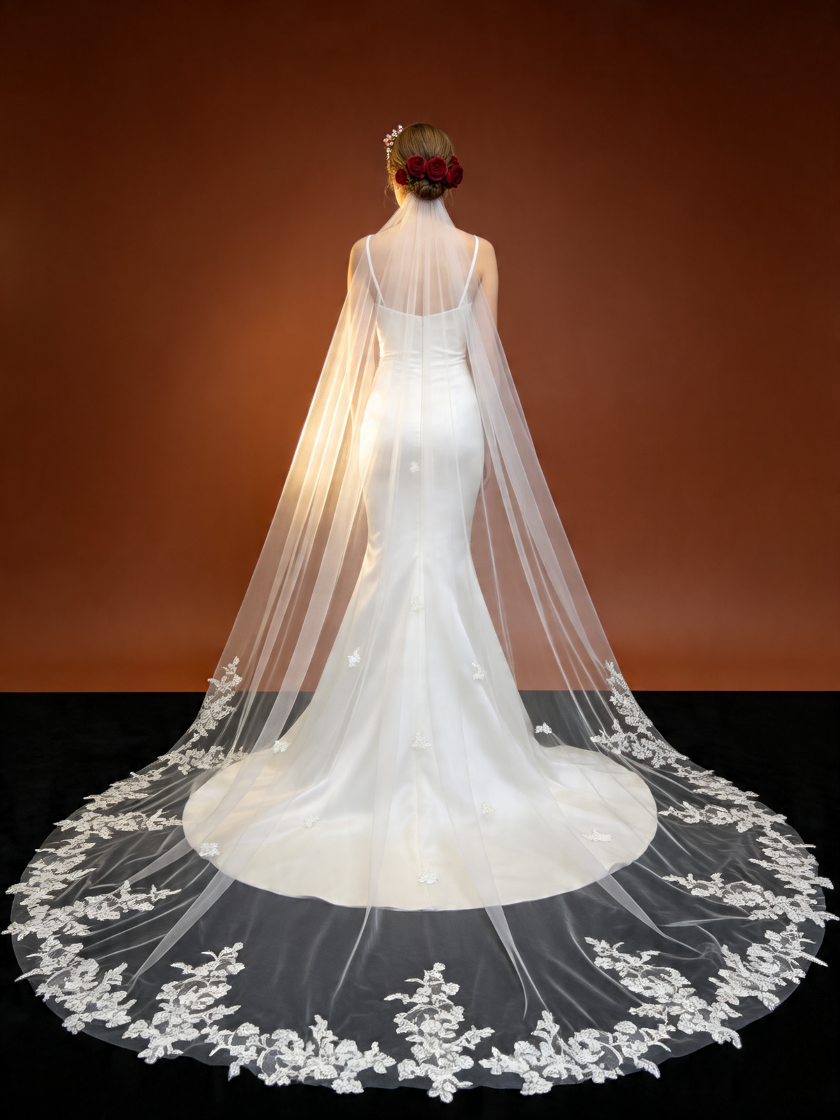 Studio shot of bride wearing airy floral lace trimmed cathedral veil, backlit to show sheer tulle and glowing floral lace hem