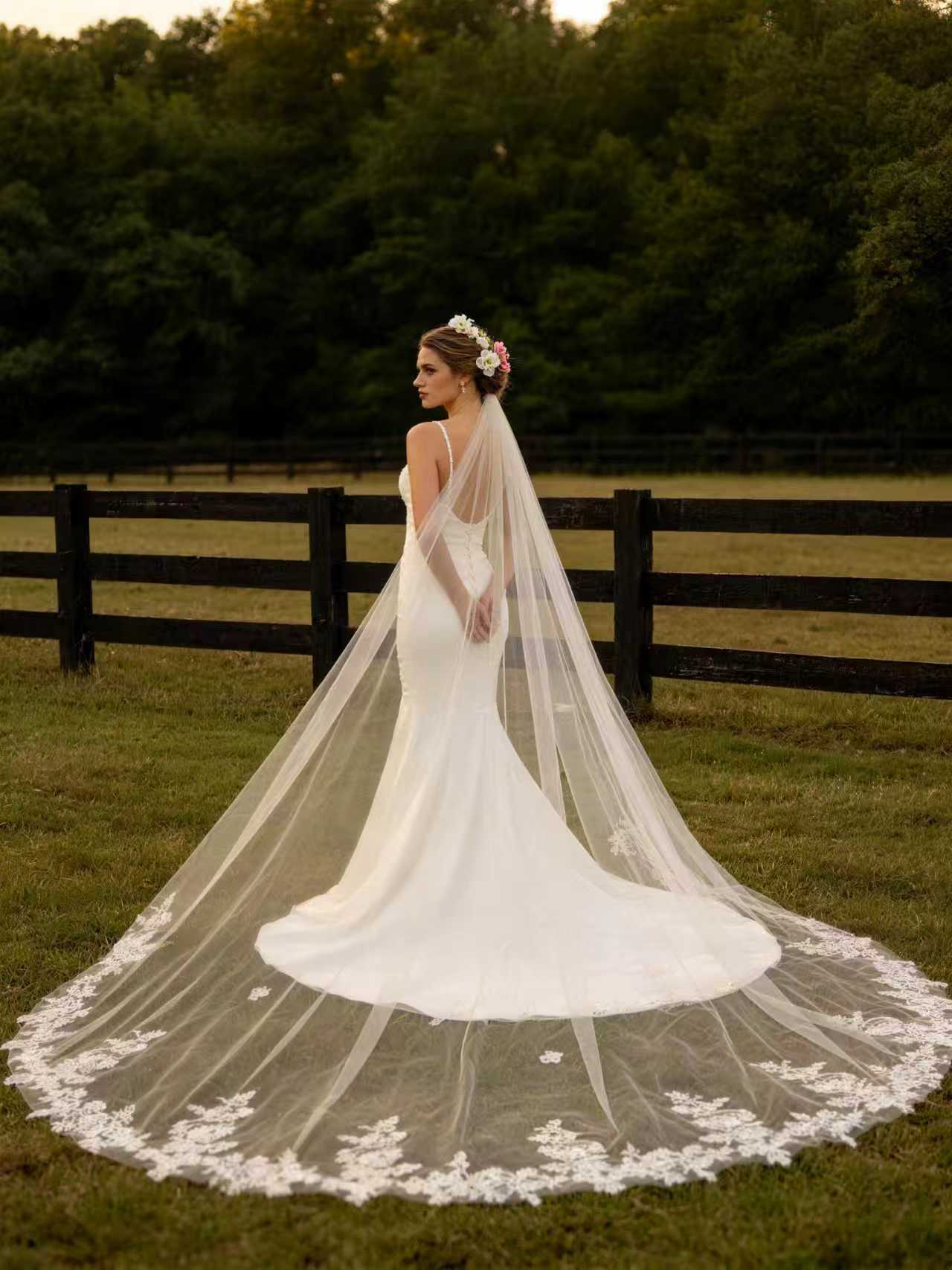 Bride wearing airy floral lace trimmed cathedral wedding veil in a forest setting, showing the full lace hem and sheer tulle