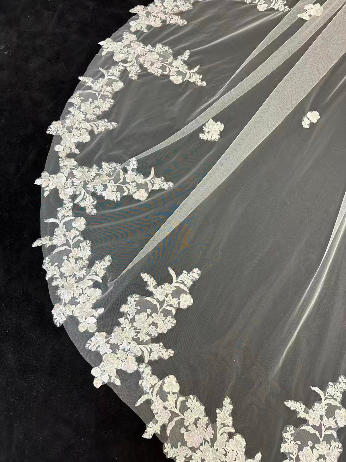 Close-up of intricate floral lace hem on luxury cathedral wedding veil, delicate bridal lace detail