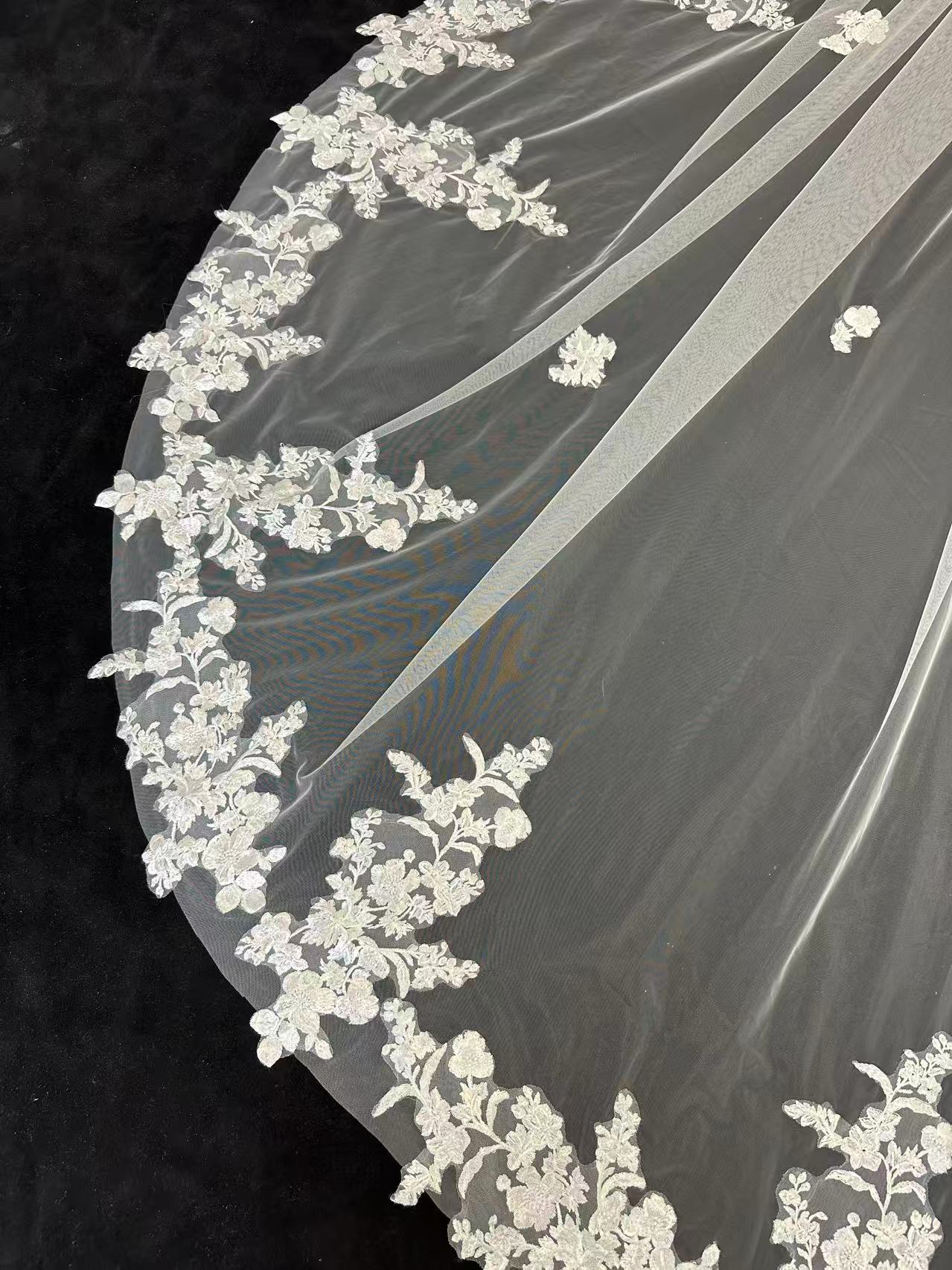 Close-up of intricate floral lace hem on luxury cathedral wedding veil, delicate bridal lace detail